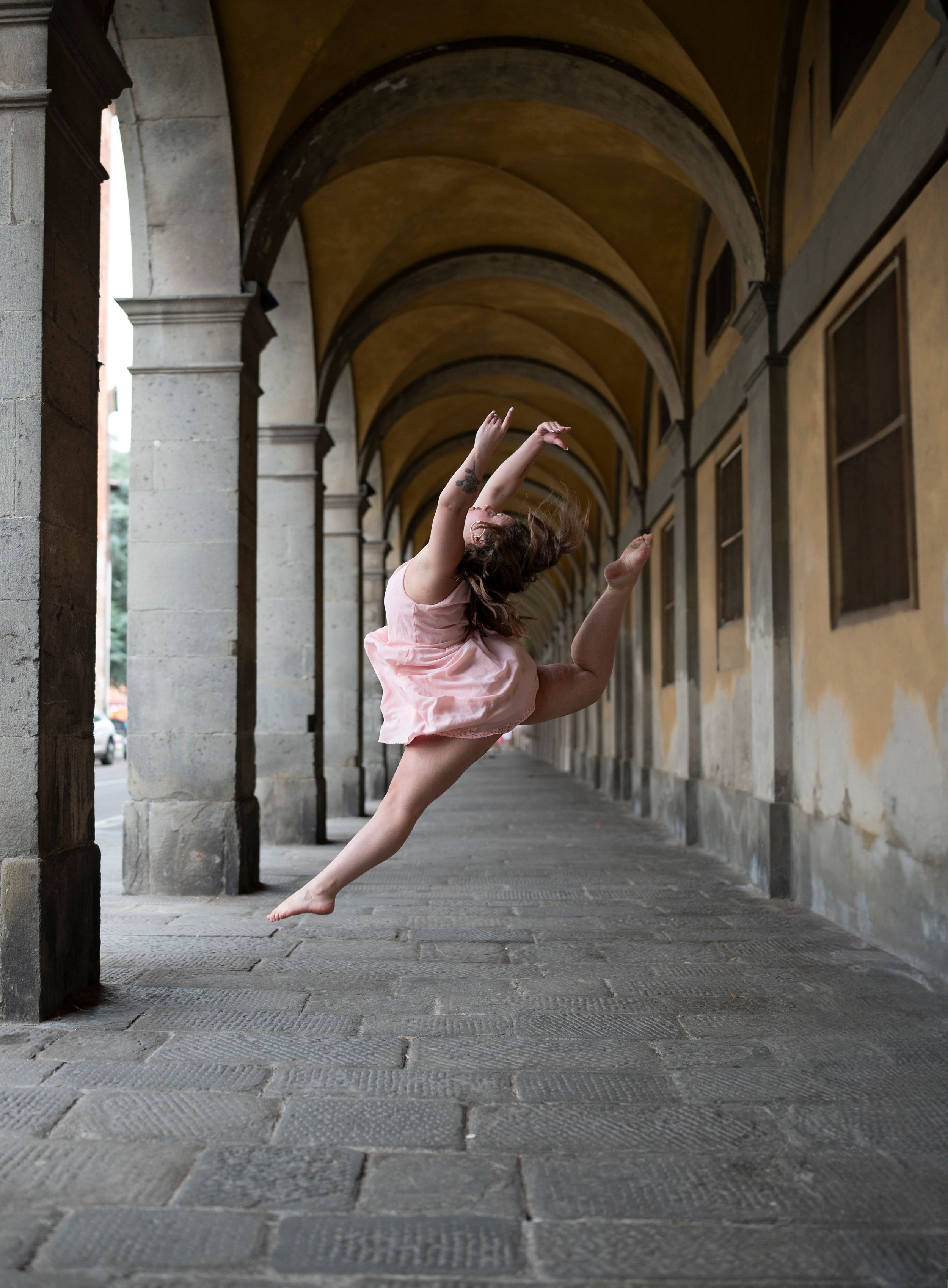 Series of artistic shots showing person in pink dress leaping through arched corridor.