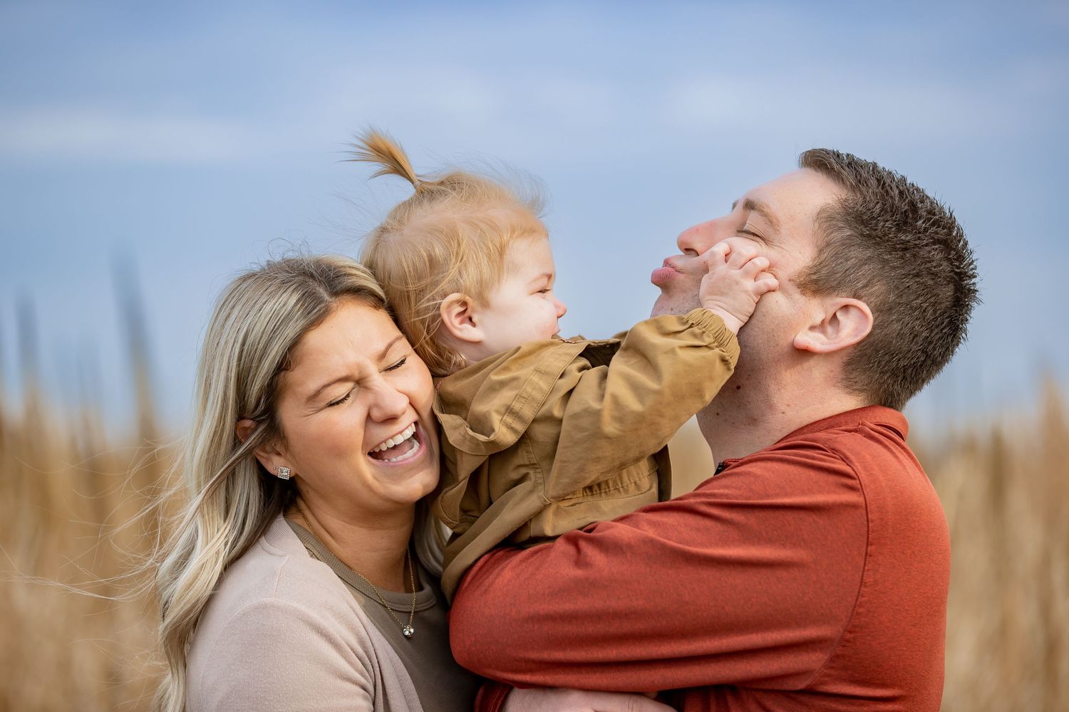 Family sharing joyful moment together in wheat field during golden hour.