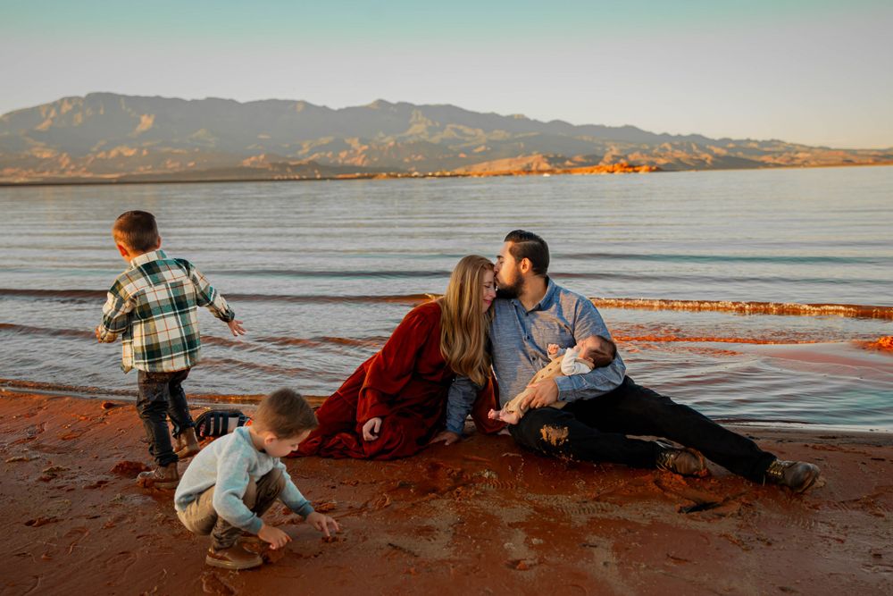 Family enjoying sunset on a beach with mountains visible in the distance.