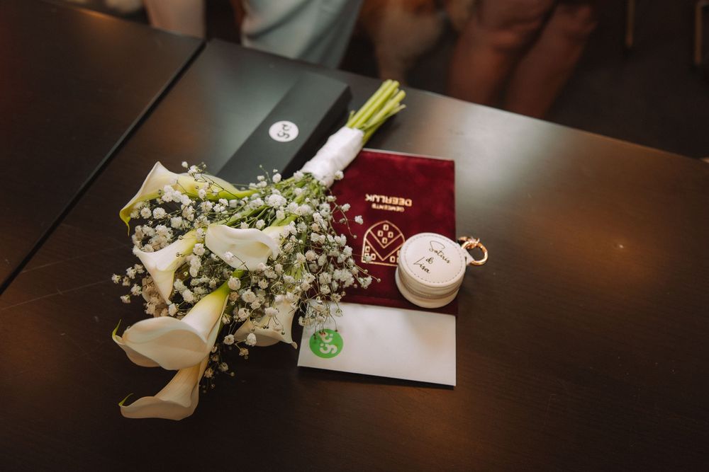 Detailshot van het boeket, trouwboekje en ringdoosje op tafel.