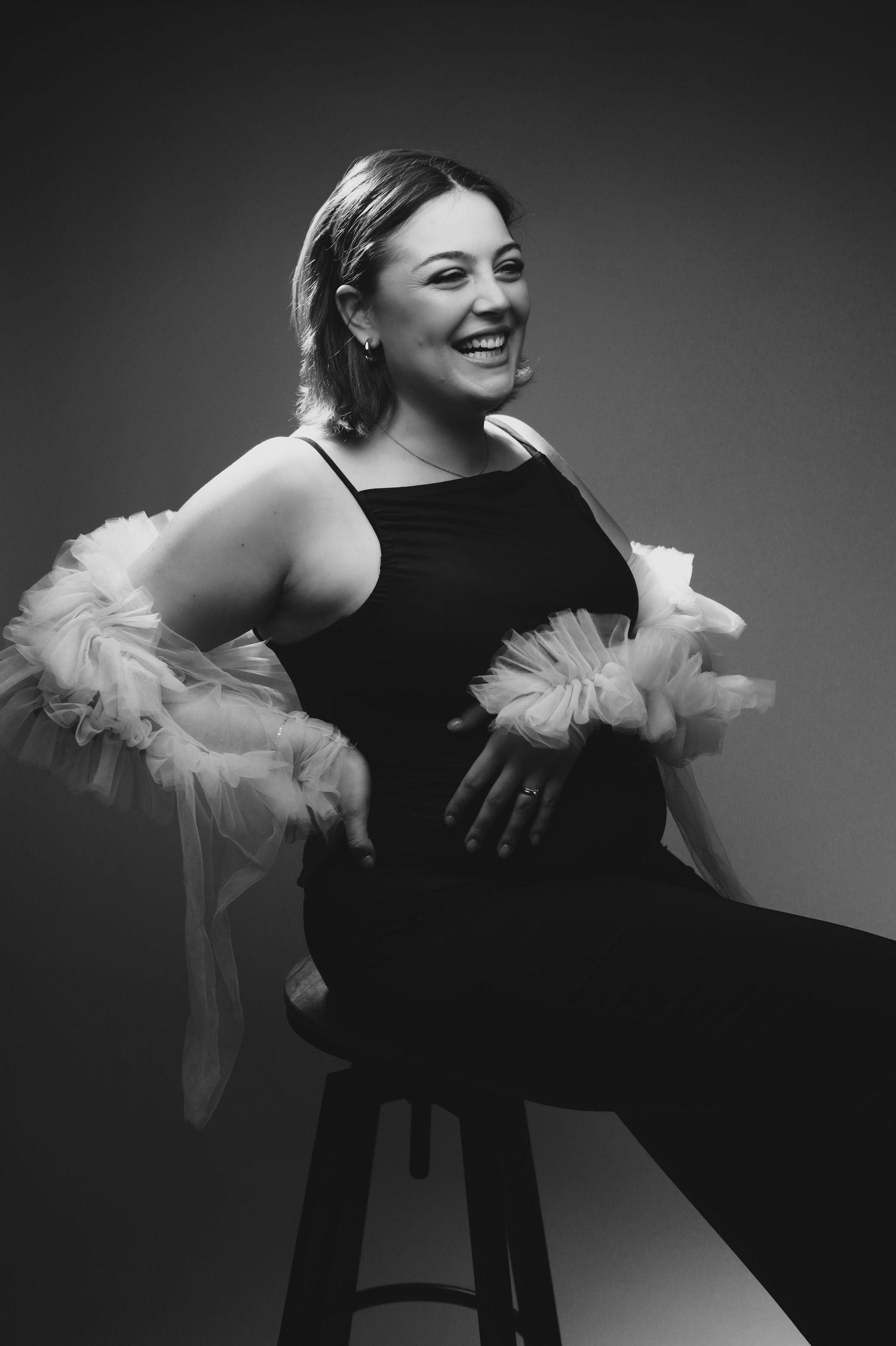 Candid portrait showing bright smile and platinum blonde hair against dark background.