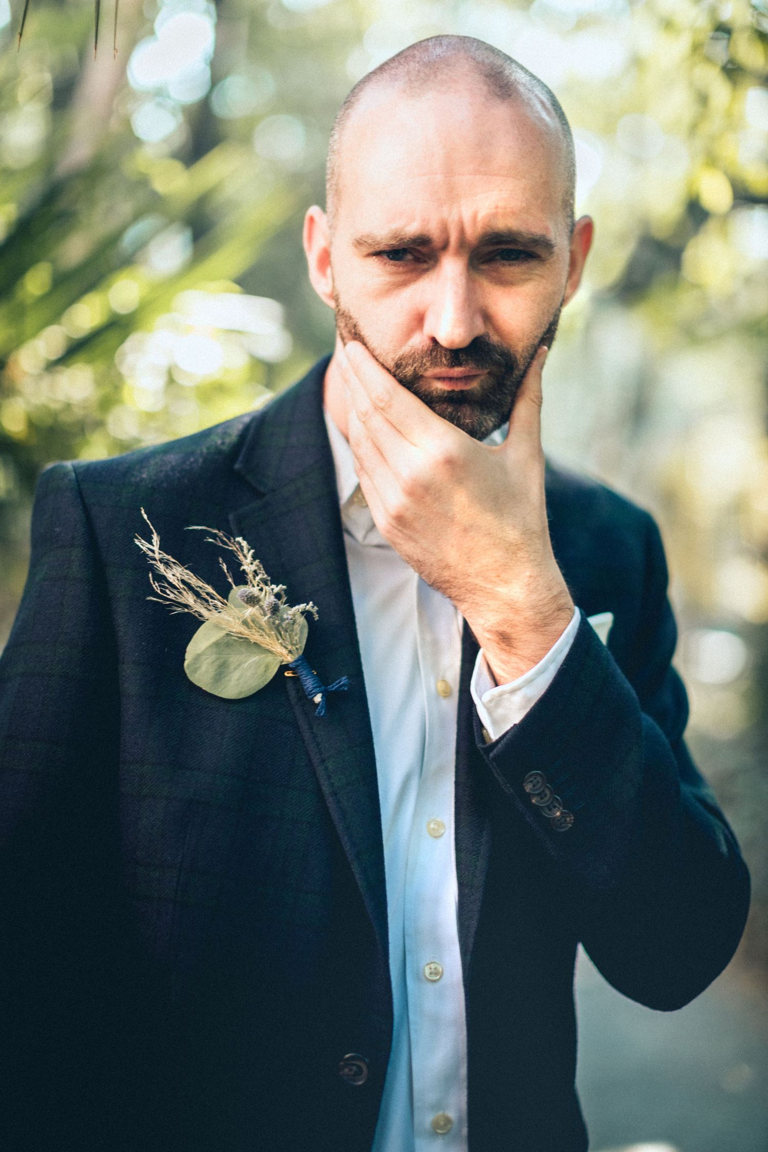 Groom in black suit sharing an emotional candid moment outdoors at a wedding ceremony.