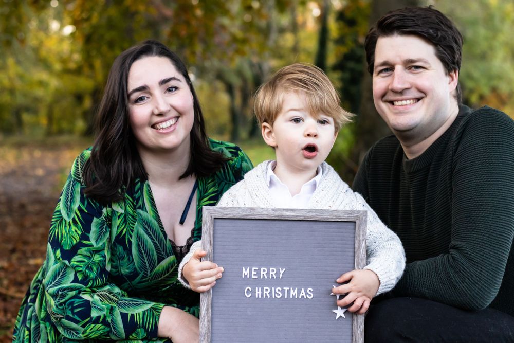 A mother, father and son hold up a sign that says Merry Christmas