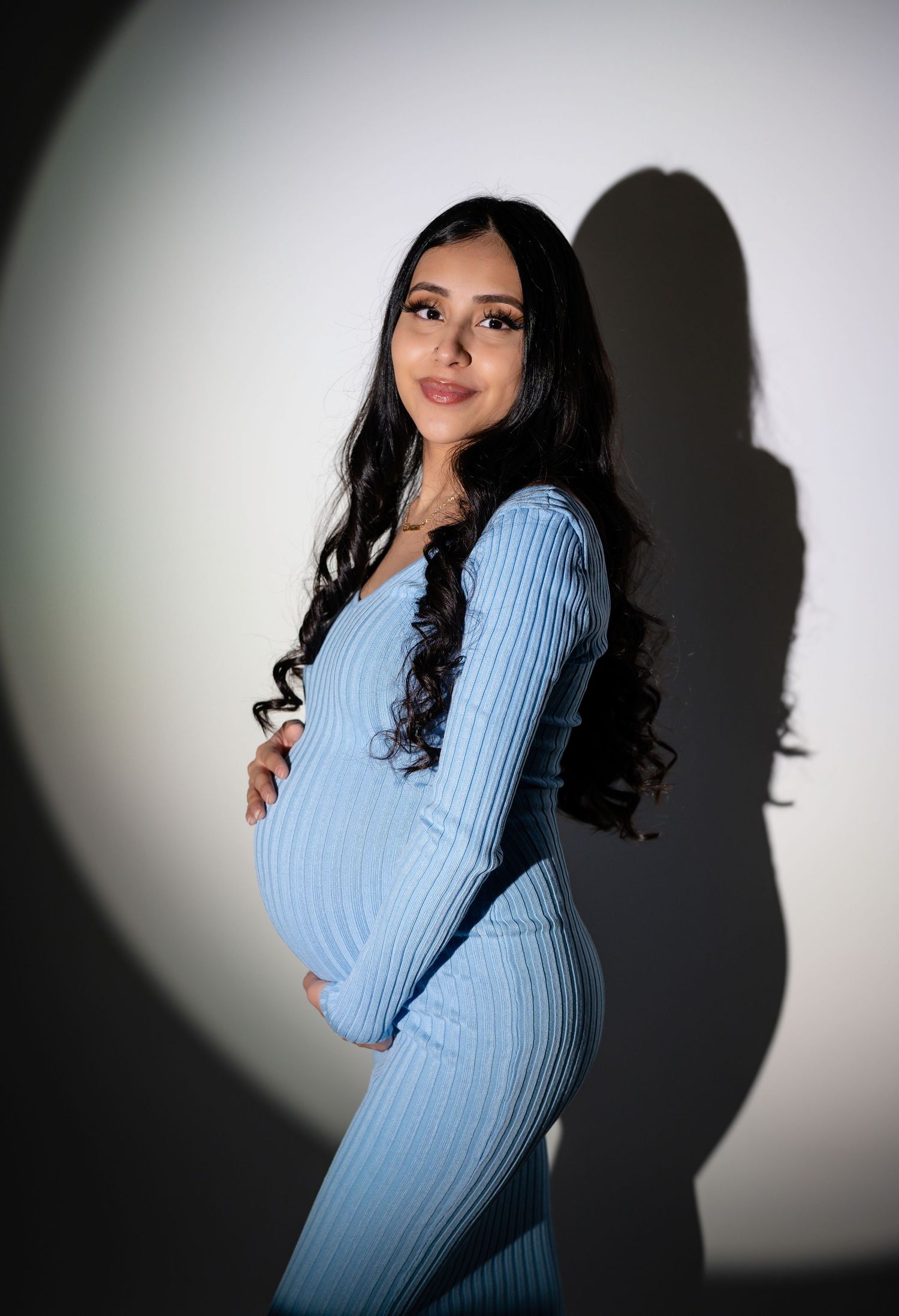Dramatic studio portraits with light blue sweater creating strong shadow effects.