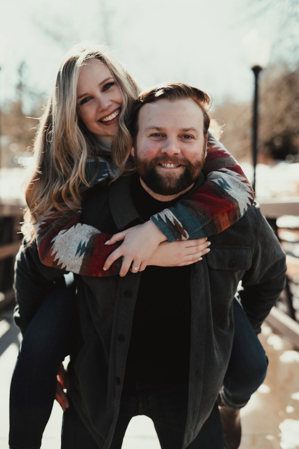 A playful piggyback ride moment between a couple wearing matching winter attire.
