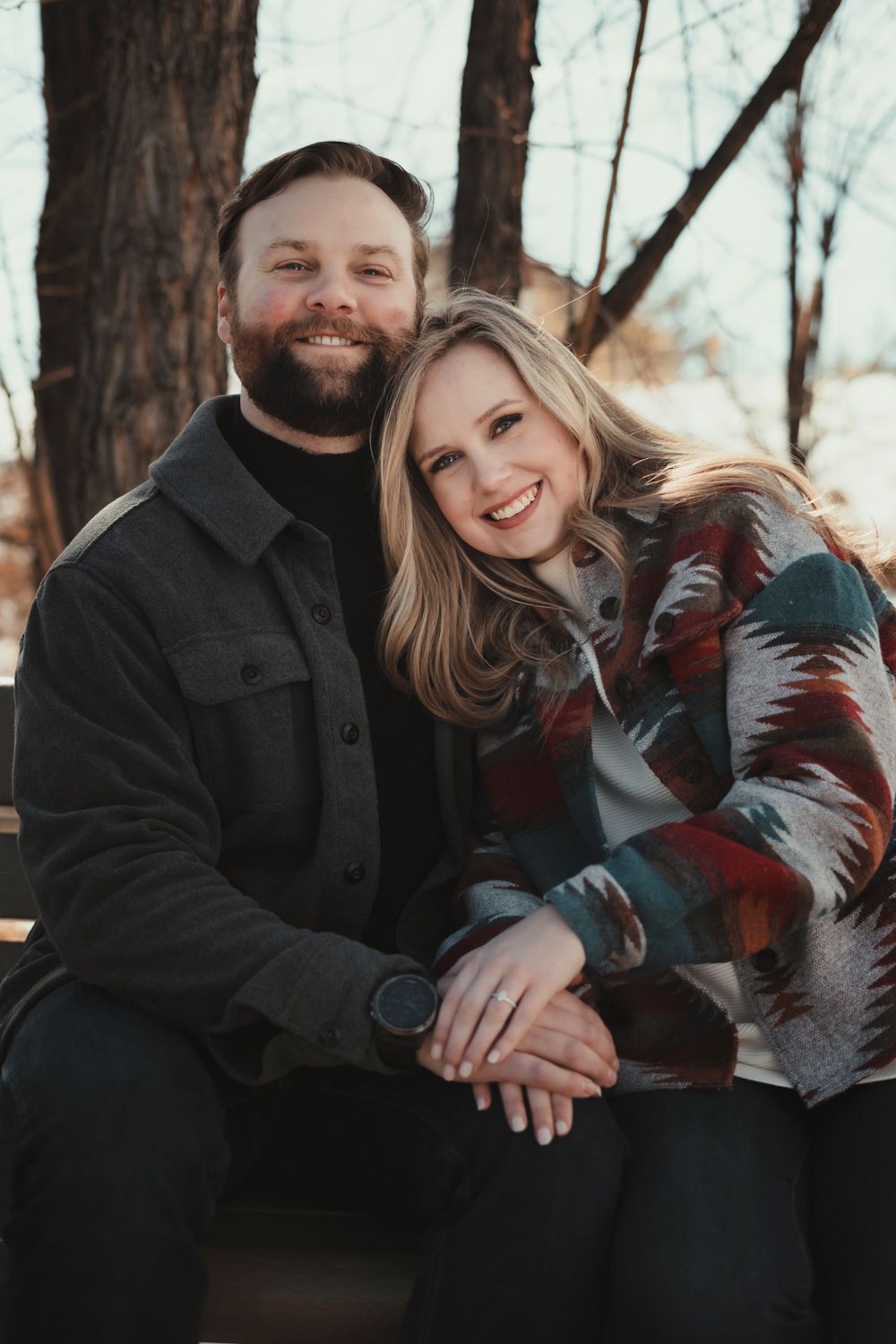 A couple sits close together on a bench, sharing a warm moment in winter attire.