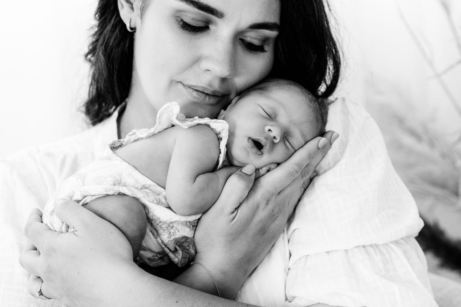 A tender black and white portrait of a parent cradling their sleeping newborn.