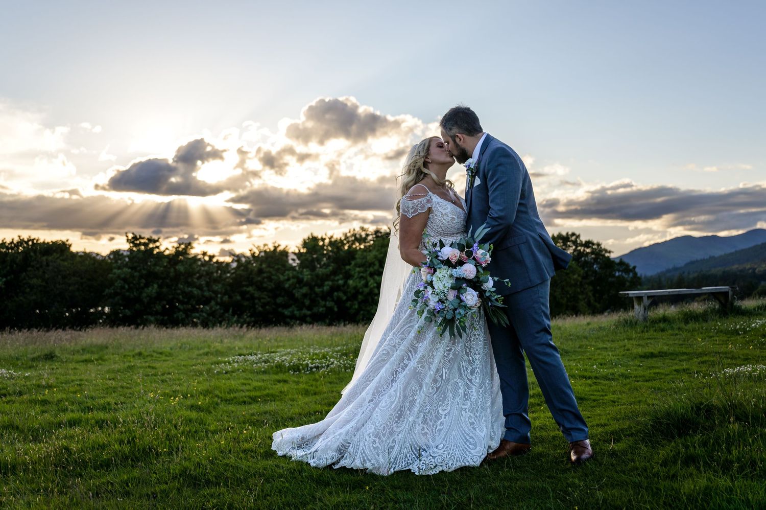 Bride and groom kissing with sun setting in background