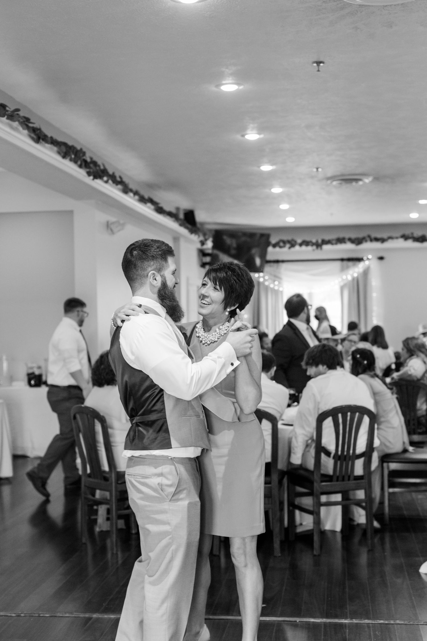 Black and white photo of couples dancing at an indoor wedding reception.