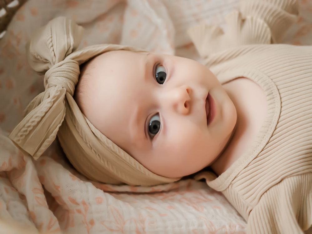 milestone baby session. six month old baby in a Moses basket and wearing a bow. Sonoma County