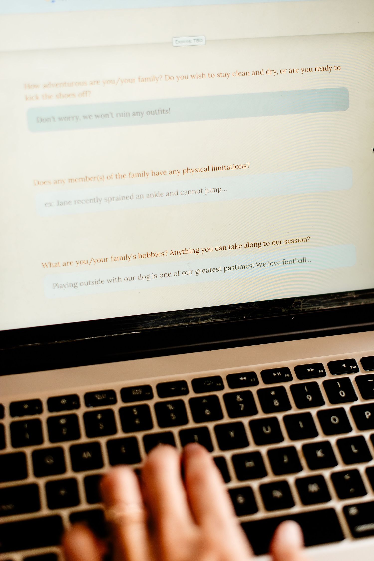 Person typing on a laptop keyboard showing text prompts and questions on the screen.