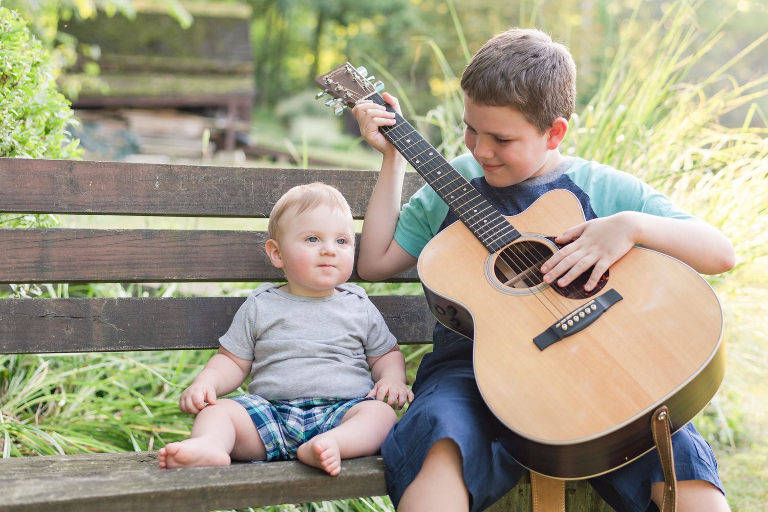 Brothers playing guitar on bench in Mars, Pennsylvania