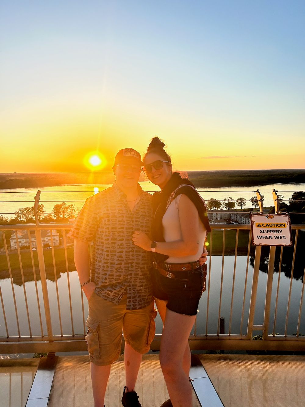 A sunset panorama sequence shows silhouettes of people watching the golden sun descend over a tranquil waterfront view.