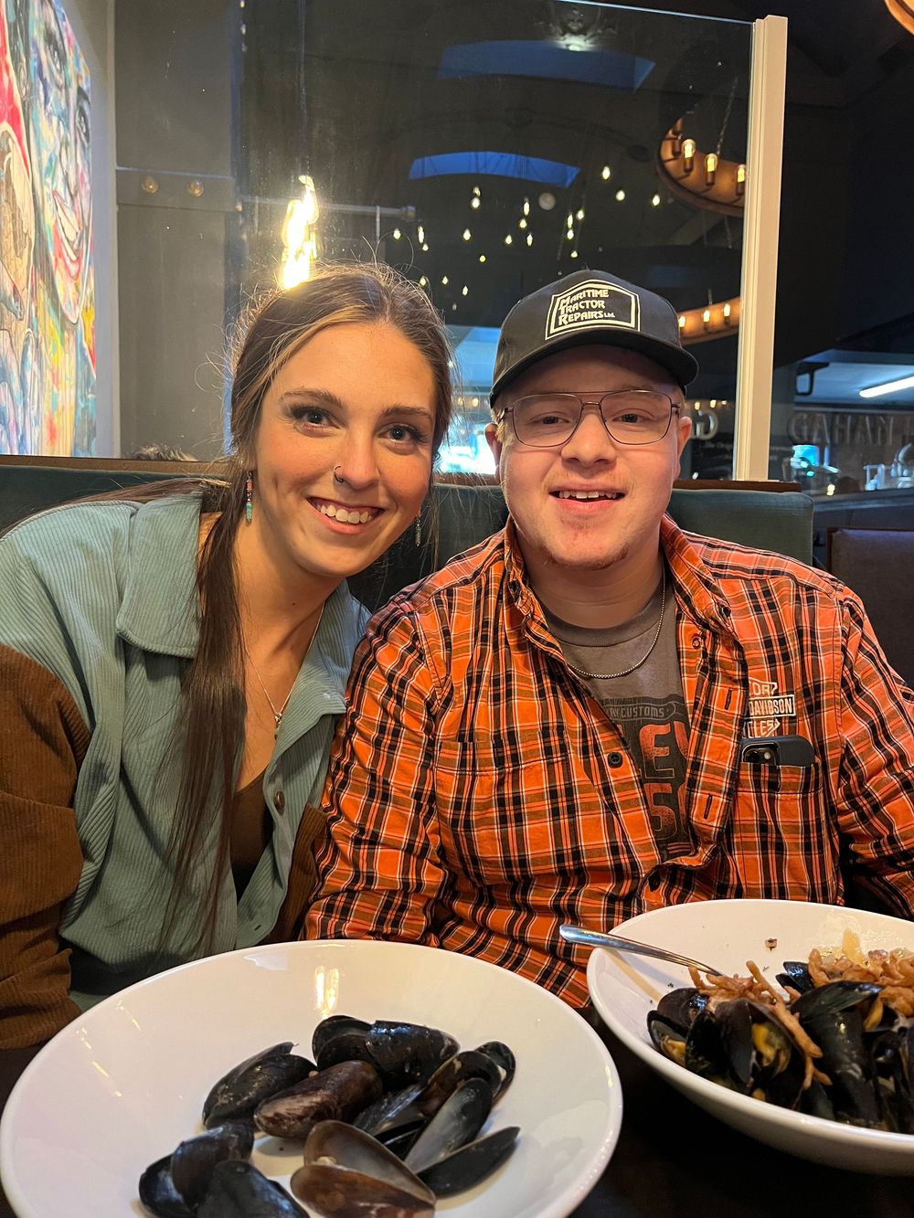 A couple dining together at a restaurant with plates of seafood and mussels on the table.