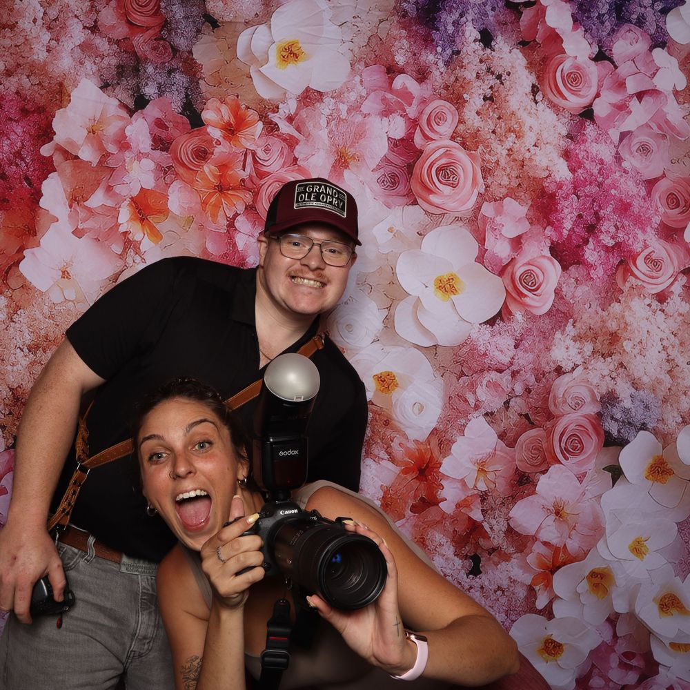 Four photo booth style images showing people posing and laughing against a pink floral backdrop at a celebration.