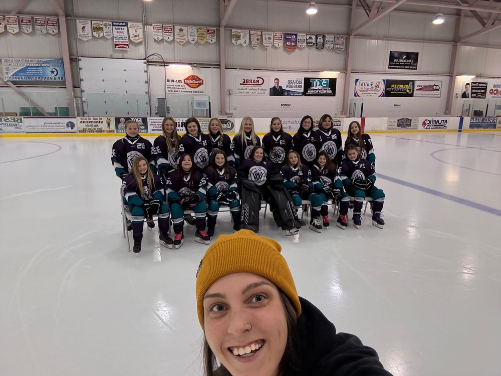 Hockey players kneel together on ice rink during team practice session.