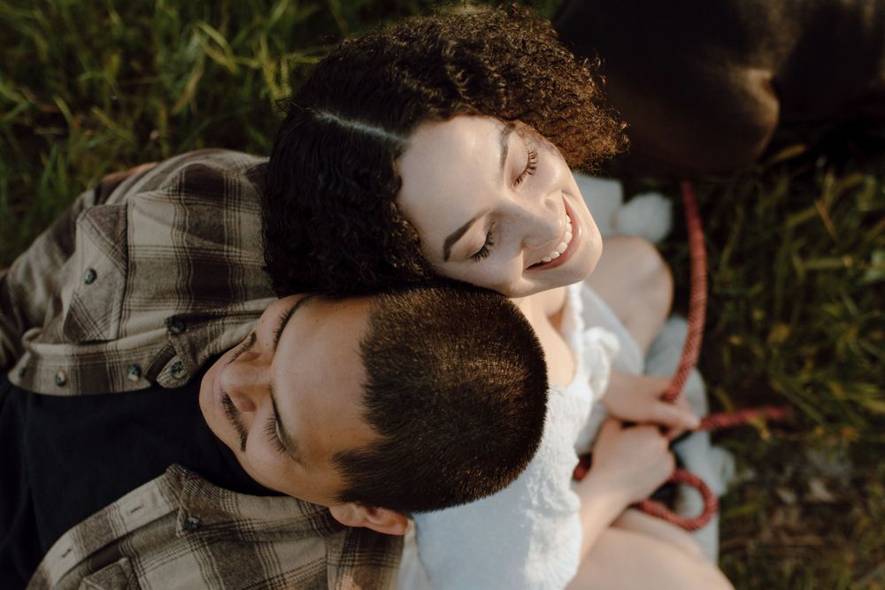 An intimate moment captured from above showing two people peacefully resting together outdoors in sunlight.