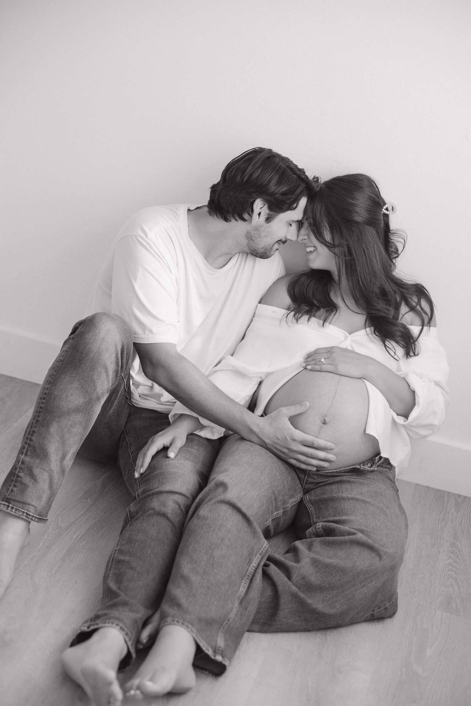 Artistic black and white maternity portrait on stool shows elegant pose.