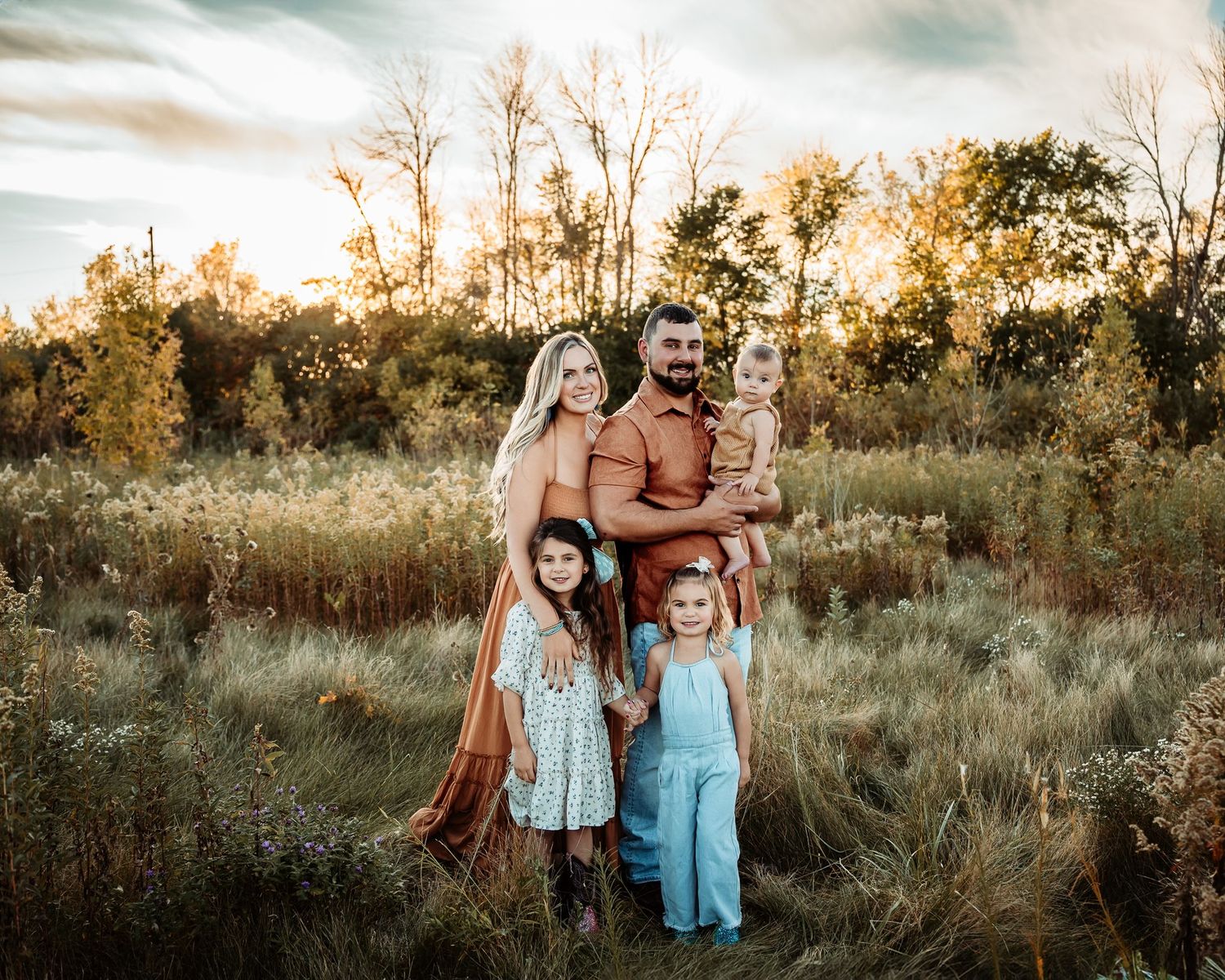 Family portrait in golden field during sunset with rustic autumn vibes.