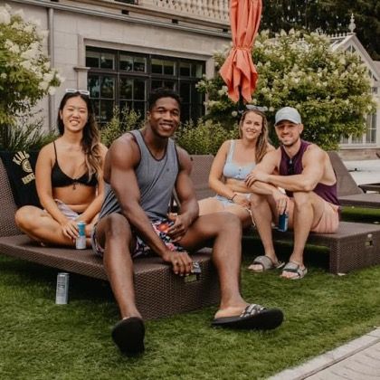 Four friends relaxing on lounge chairs by a pool on a sunny day.
