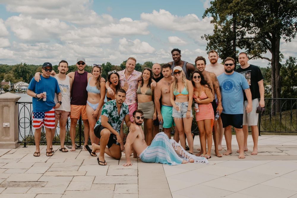 Group of friends in swimwear posing together outdoors near a luxury pool.