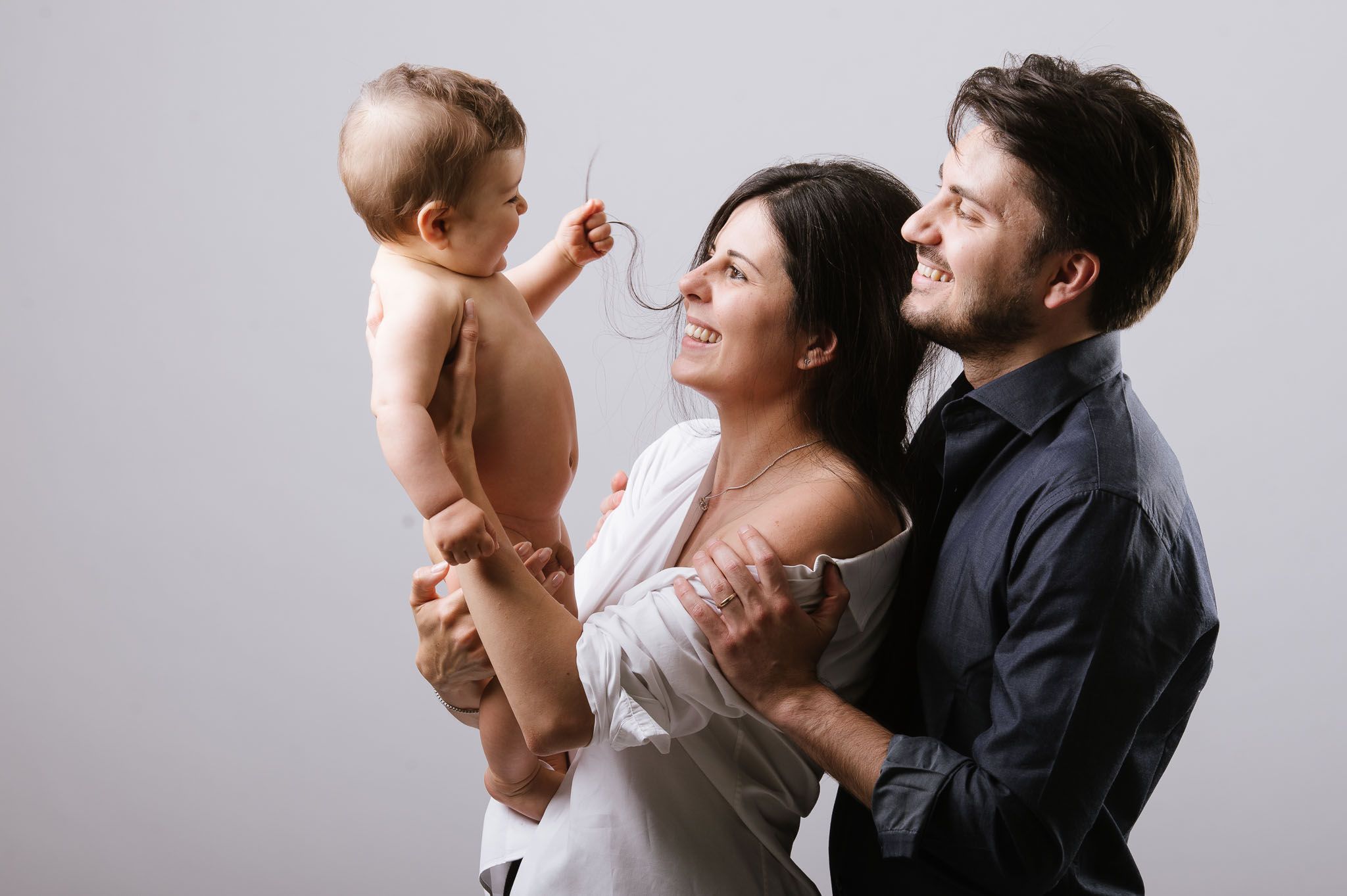 A joyful family moment captured against a light gray studio background.