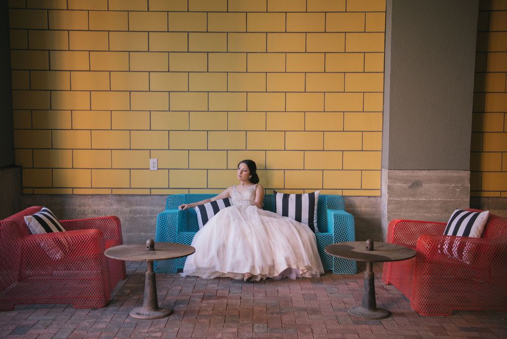 girl sitting down on couch. yellow walls. pink dress. The Pearl. San Antonio, Texas. Wedding photographer