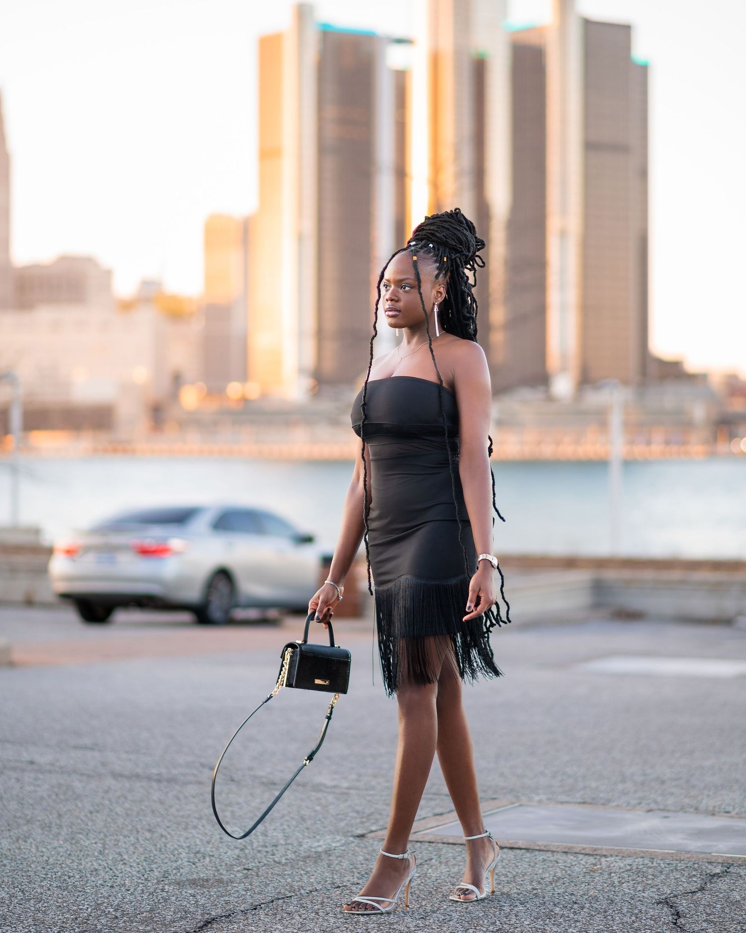 Urban photoshoot at sunset wearing black dress near city buildings.