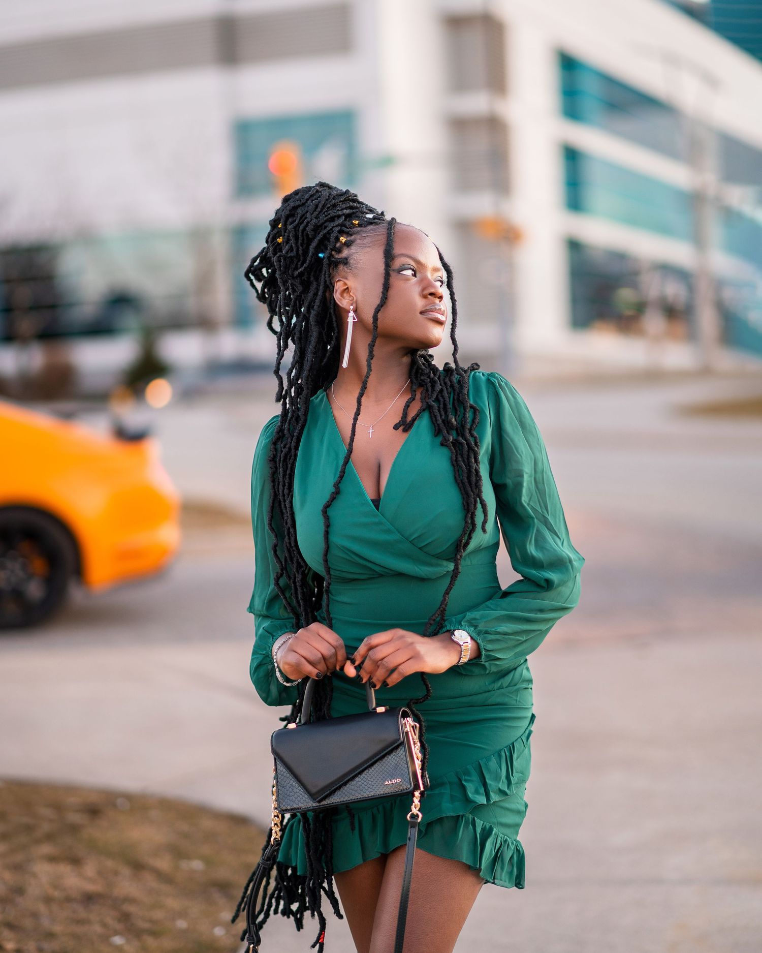 Street style photography featuring emerald green outfit with black handbag accessory.
