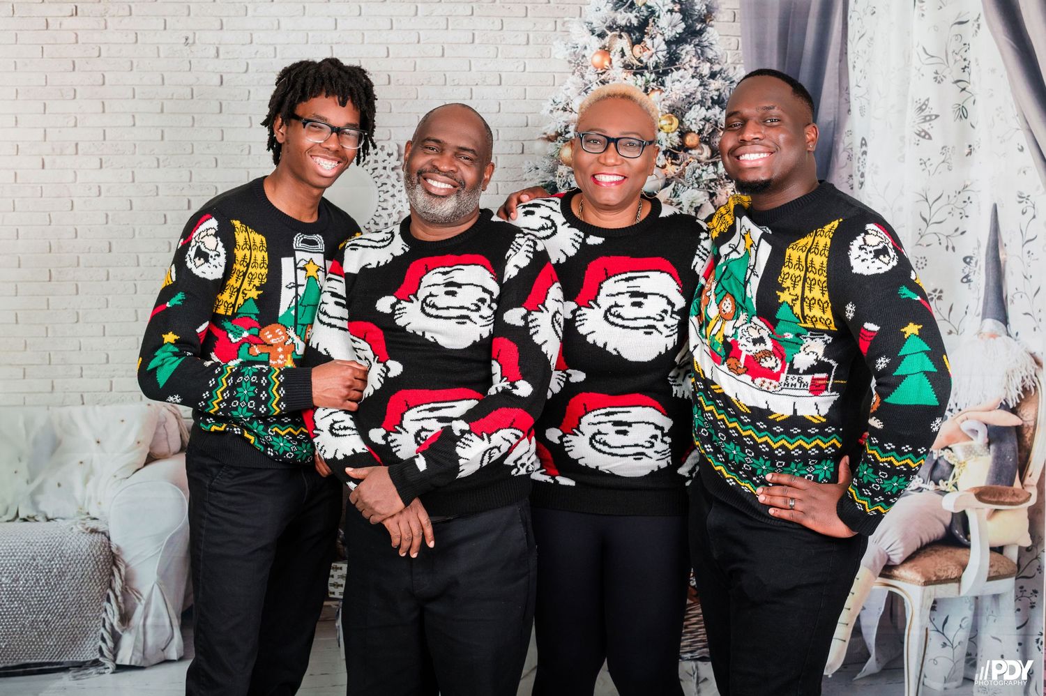 Group wearing coordinated Christmas sweaters poses for holiday photos.