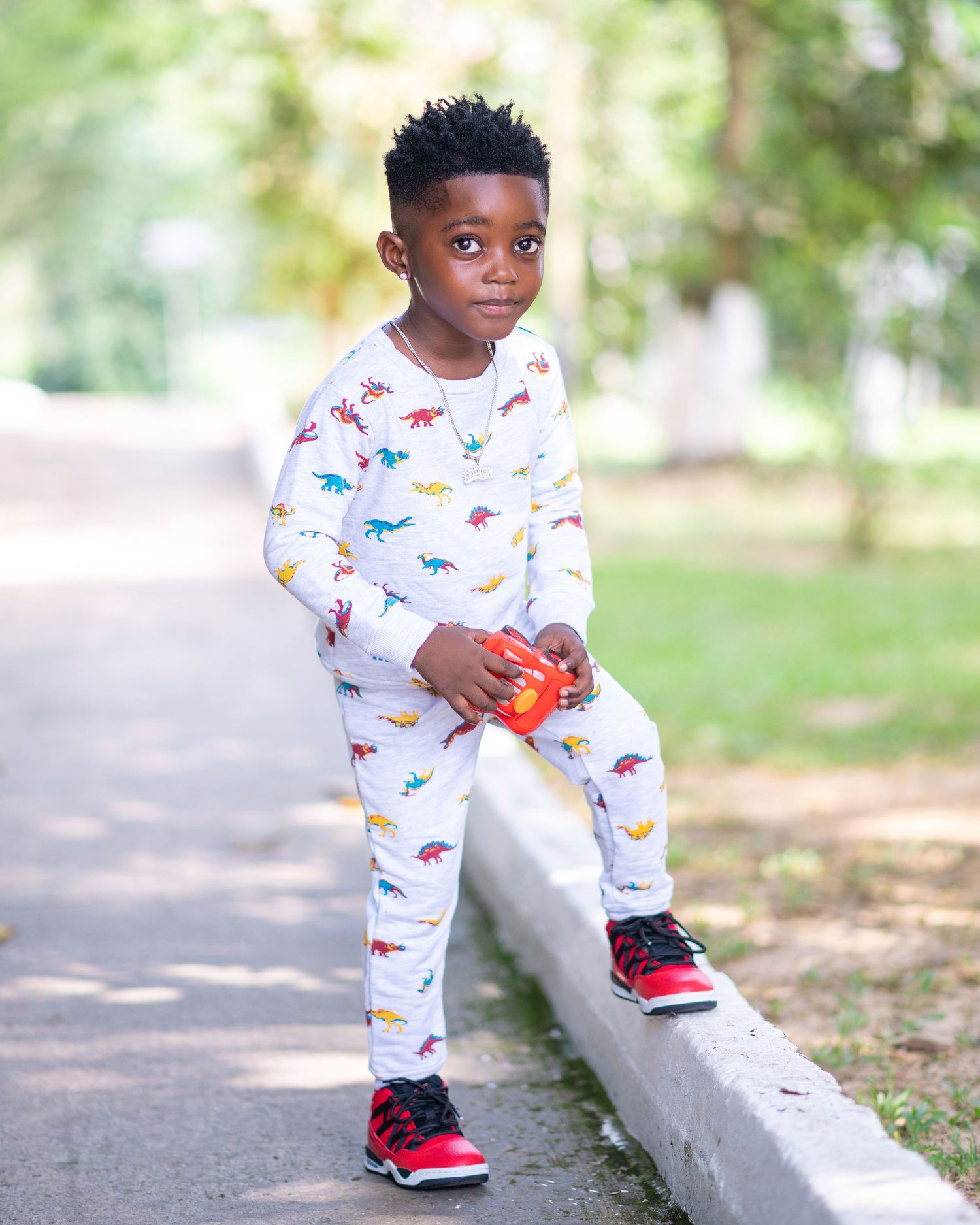 Toddler in dinosaur print pajamas playing outdoors on concrete steps.