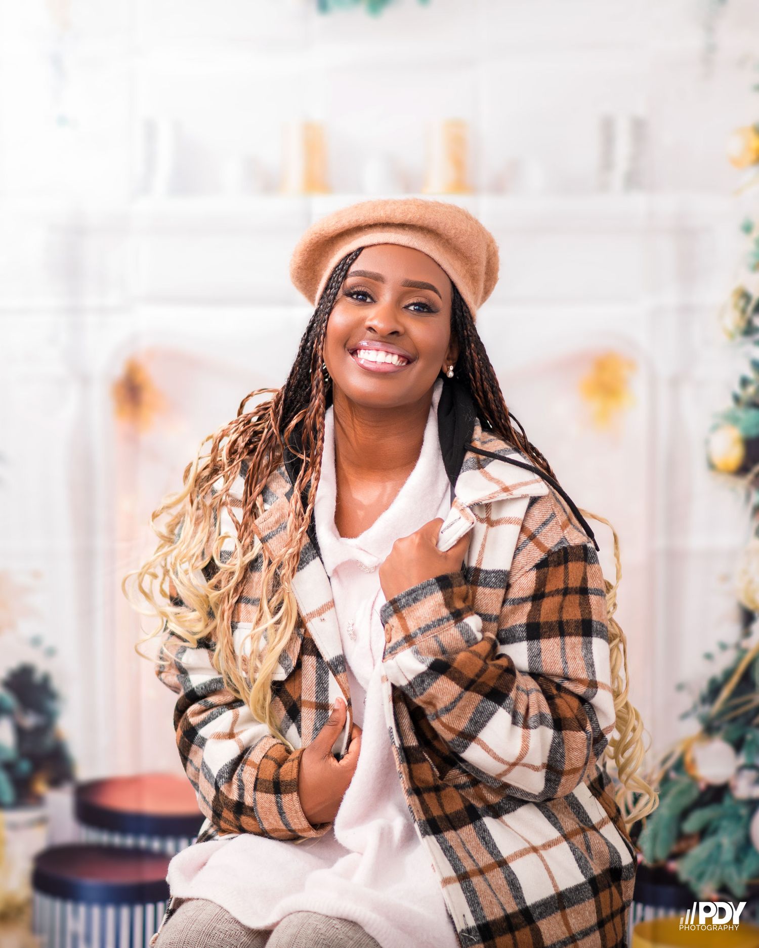 Cozy winter fashion with plaid jacket and beret in front of decorated Christmas fireplace.