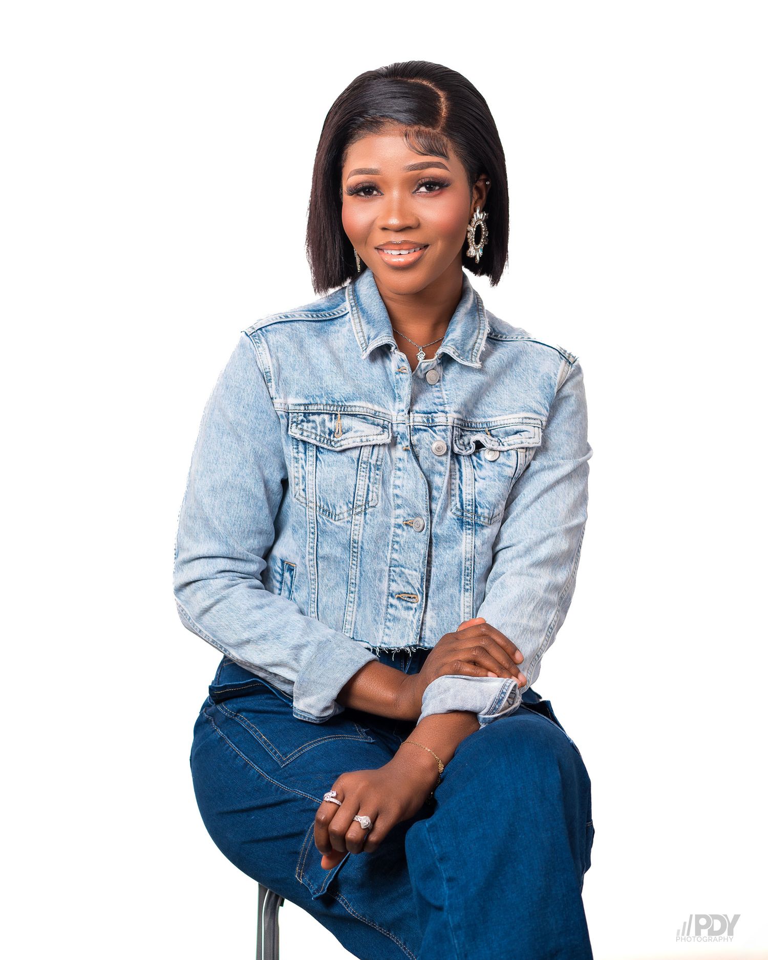 Casual denim on denim outfit featuring light wash jacket and dark jeans while seated.