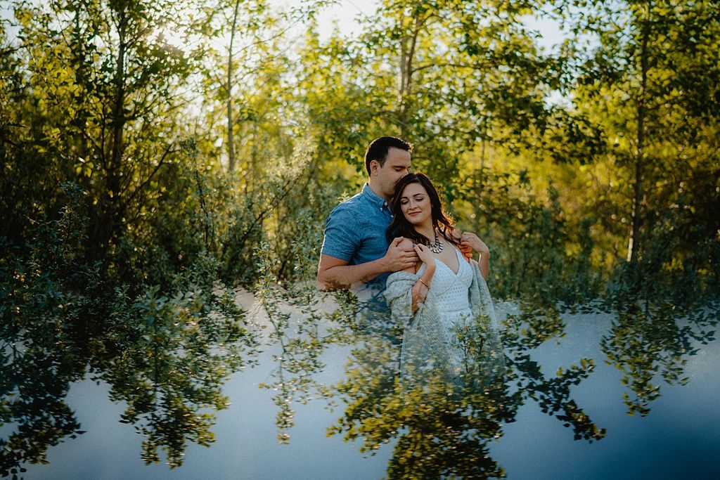 Summer engagement photos in a lush green forest setting with dappled sunlight.