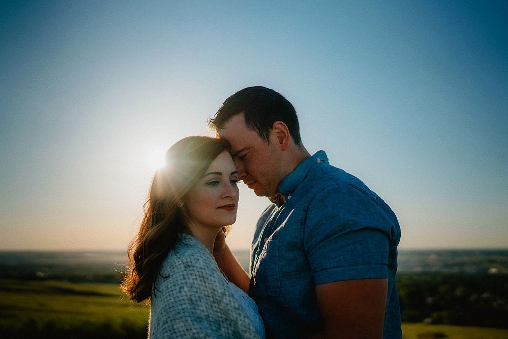 Intimate silhouette of couple embracing against sunset sky in countryside setting.