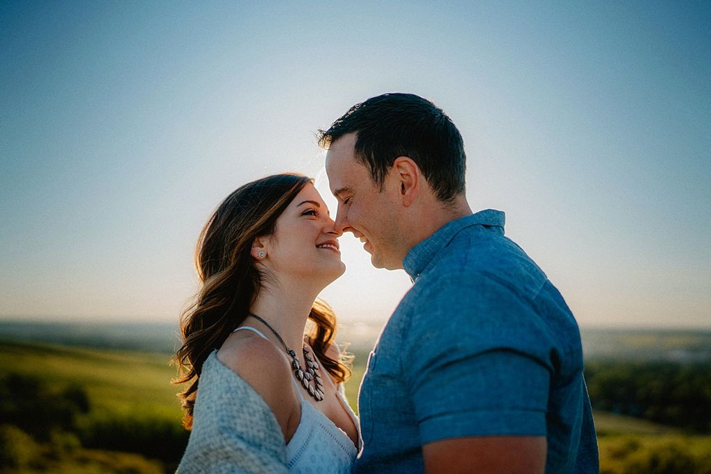 Romantic moment between couple in blue and white against bright sky backdrop.