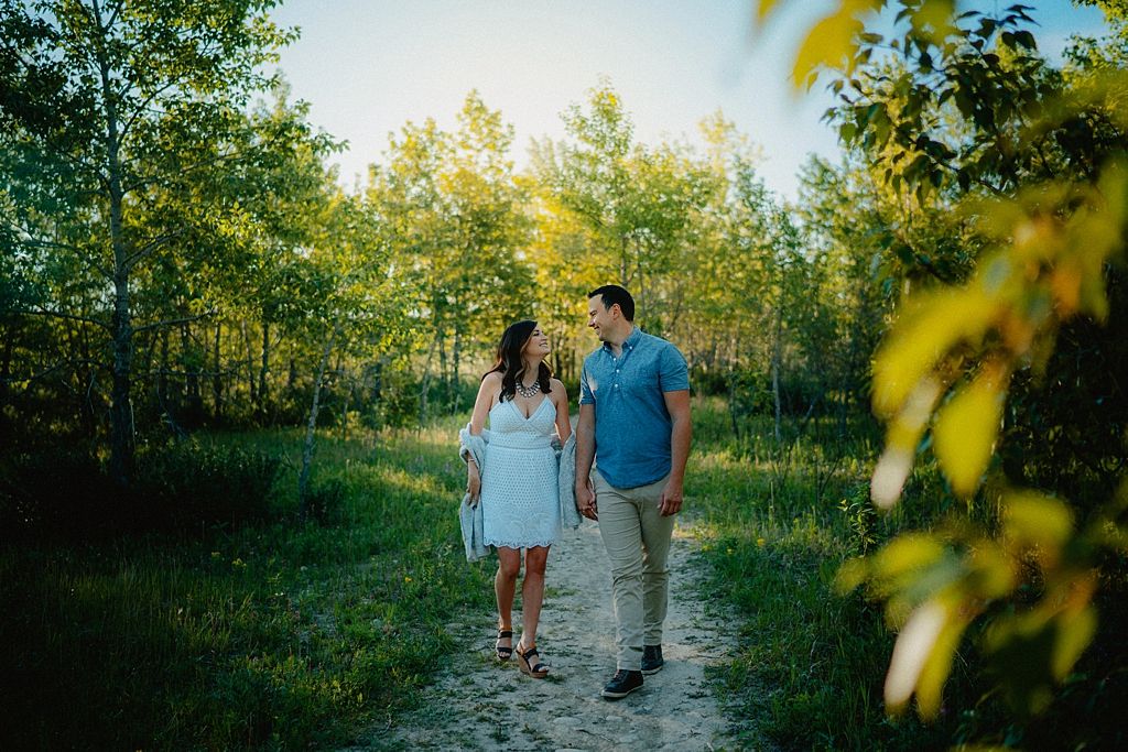 A couple walks hand in hand along a scenic nature trail during golden hour.