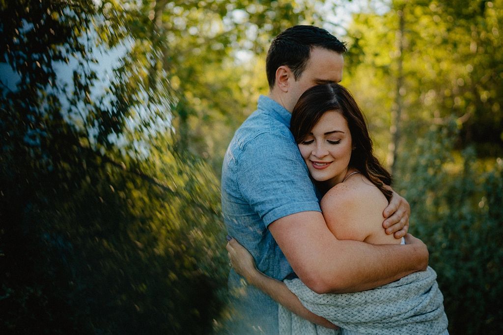 A tender embrace between two people photographed in a natural woodland setting.