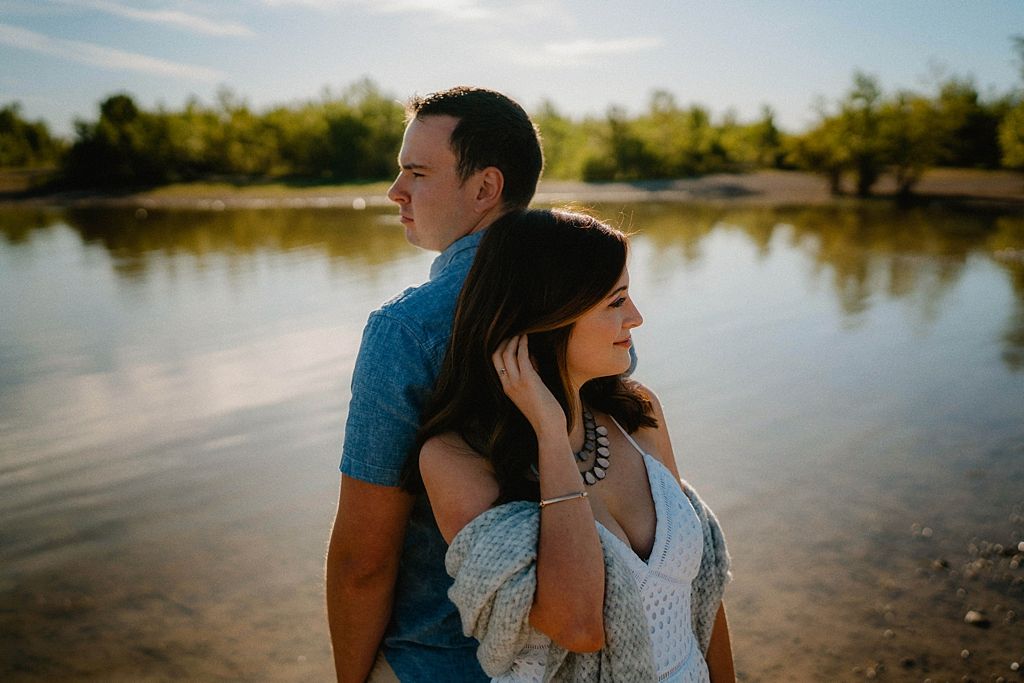 A couple shares a tender moment by a serene lake during golden hour.