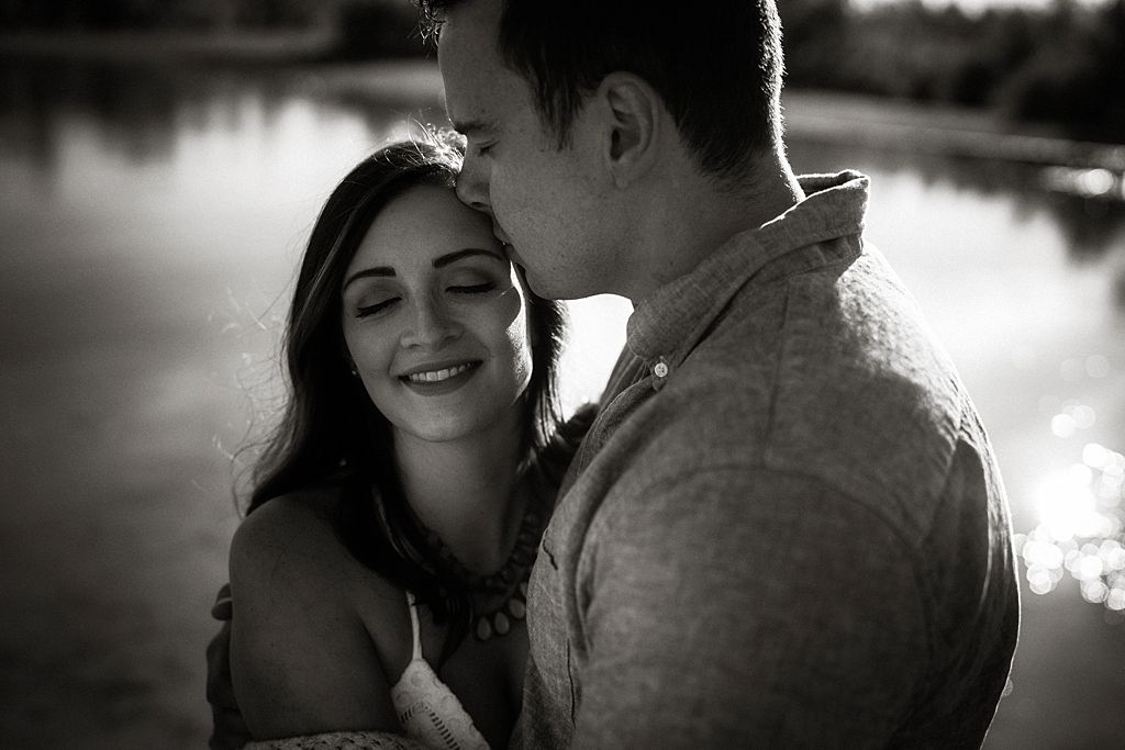 Black and white portrait of a romantic moment captured in dramatic lighting.