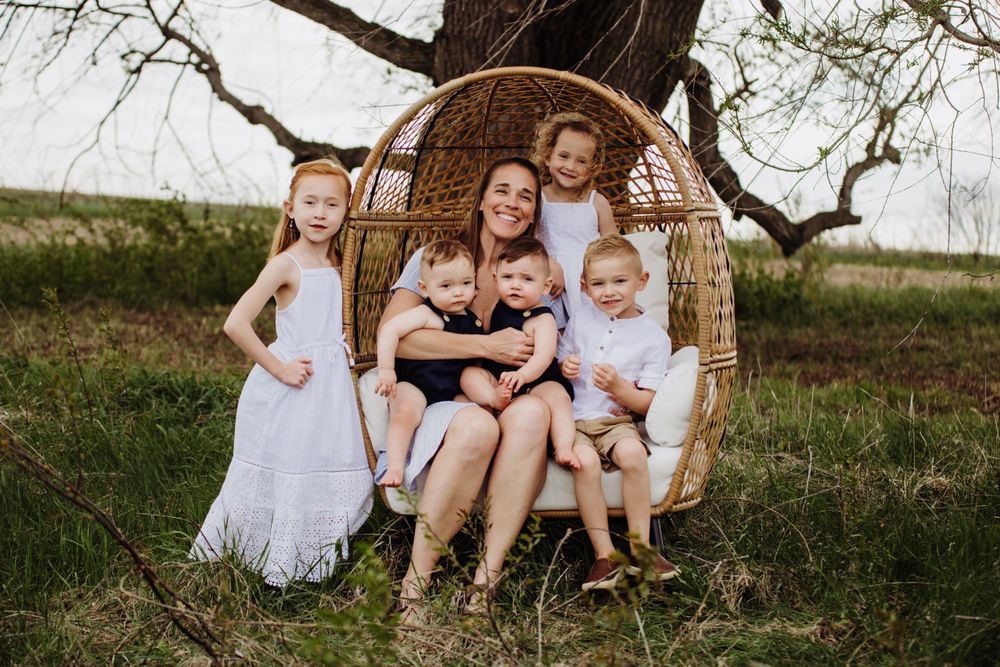 Group photo session featuring a hanging rattan chair in an outdoor natural environment.