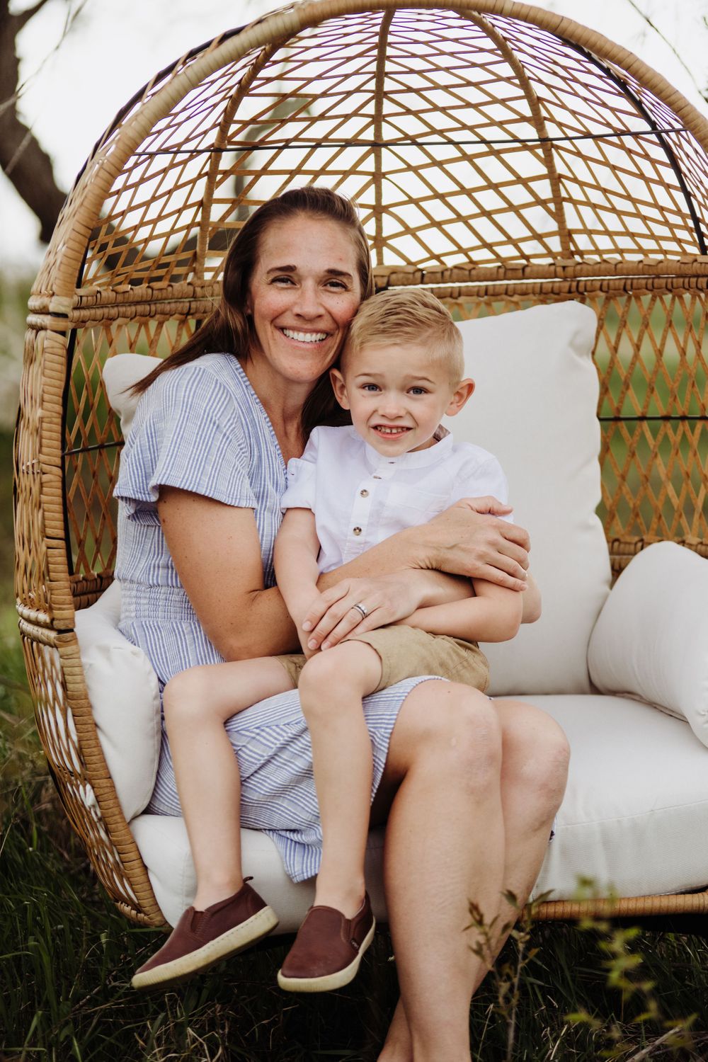 Candid moments captured in a suspended wicker chair outdoors during golden hour.