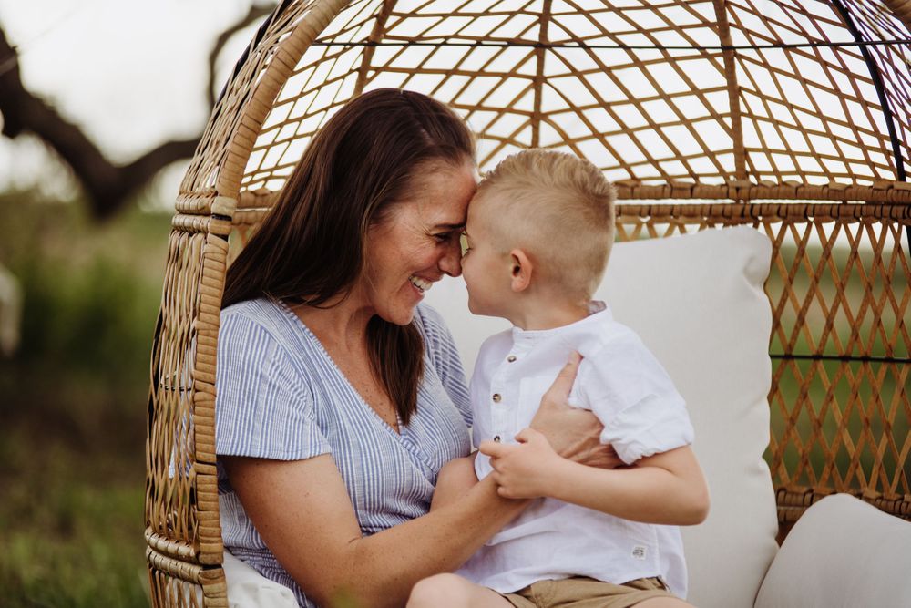 Sweet family moments shared in a suspended wicker egg chair outdoors.