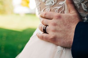 Close-up of wedding rings and lace dress details.