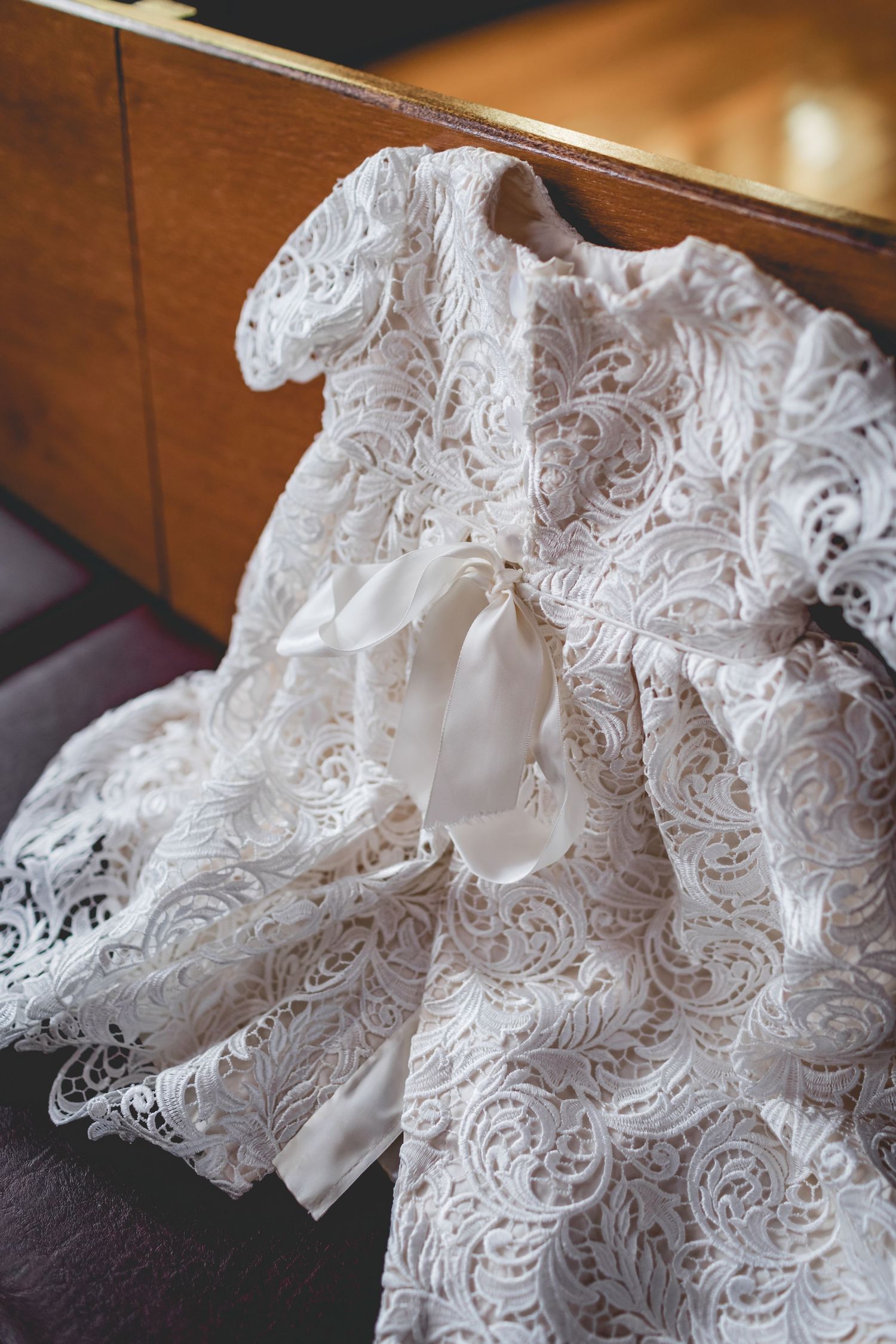 Delicate white lace wedding dress fabric with floral patterns and ribbon details draped elegantly.