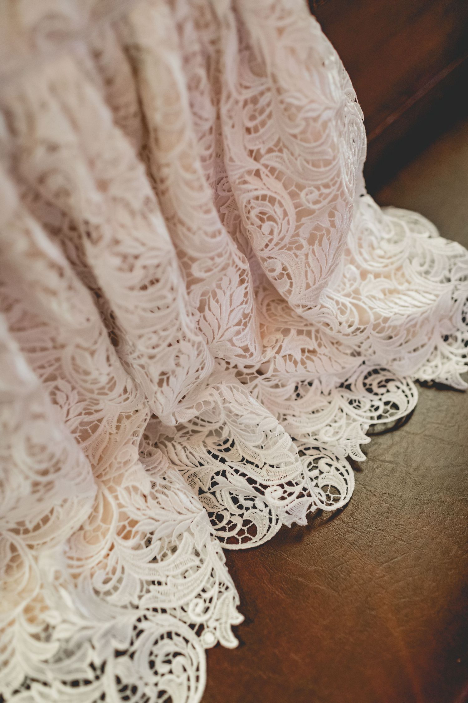 Intricate lace detail of white baptismal gown with scalloped edges.