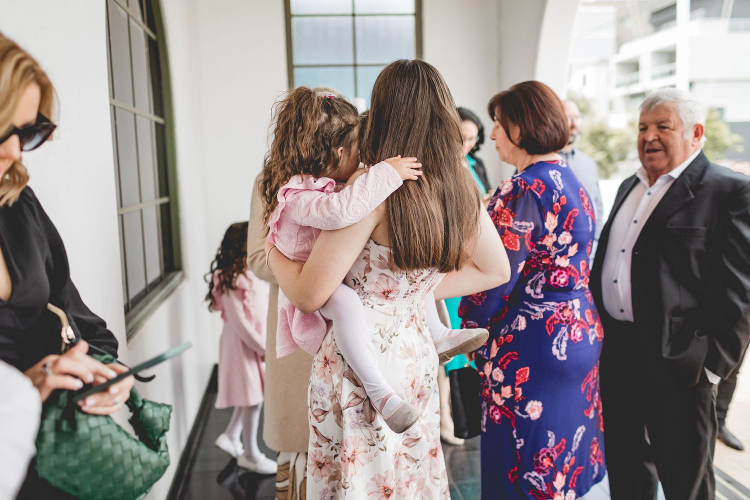 Wedding guests gathered on a porch wearing colorful floral dresses and formal attire.