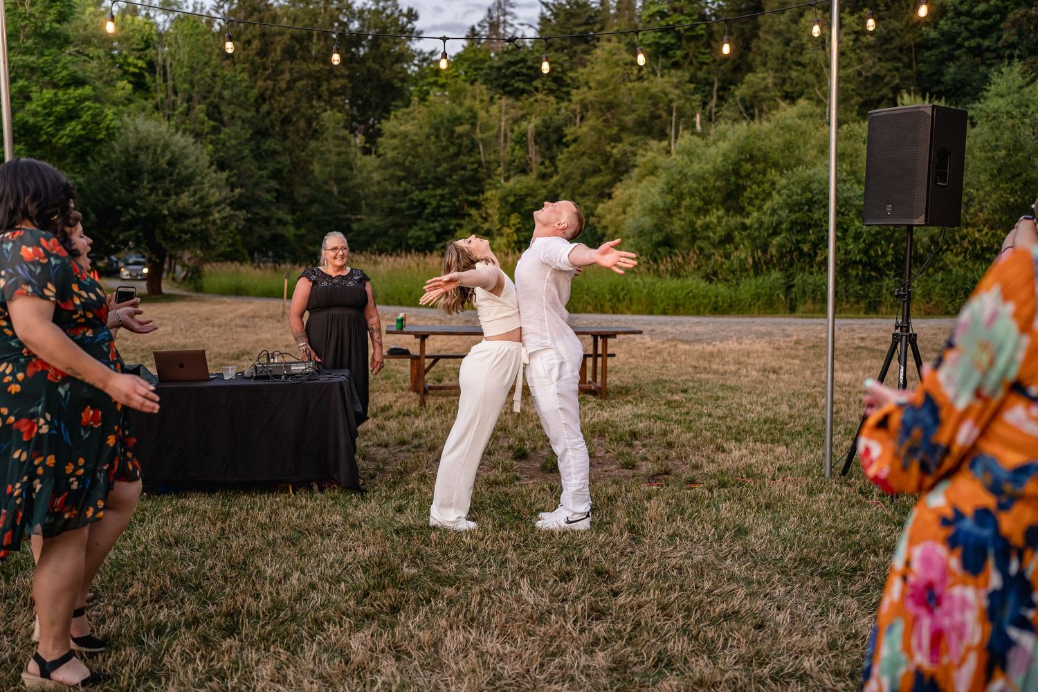 Couple dancing together at outdoor wedding reception with DJ setup visible.
