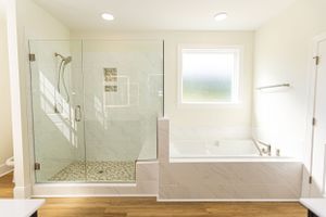 Bright white bathroom interior with glass shower enclosure and recessed lighting.