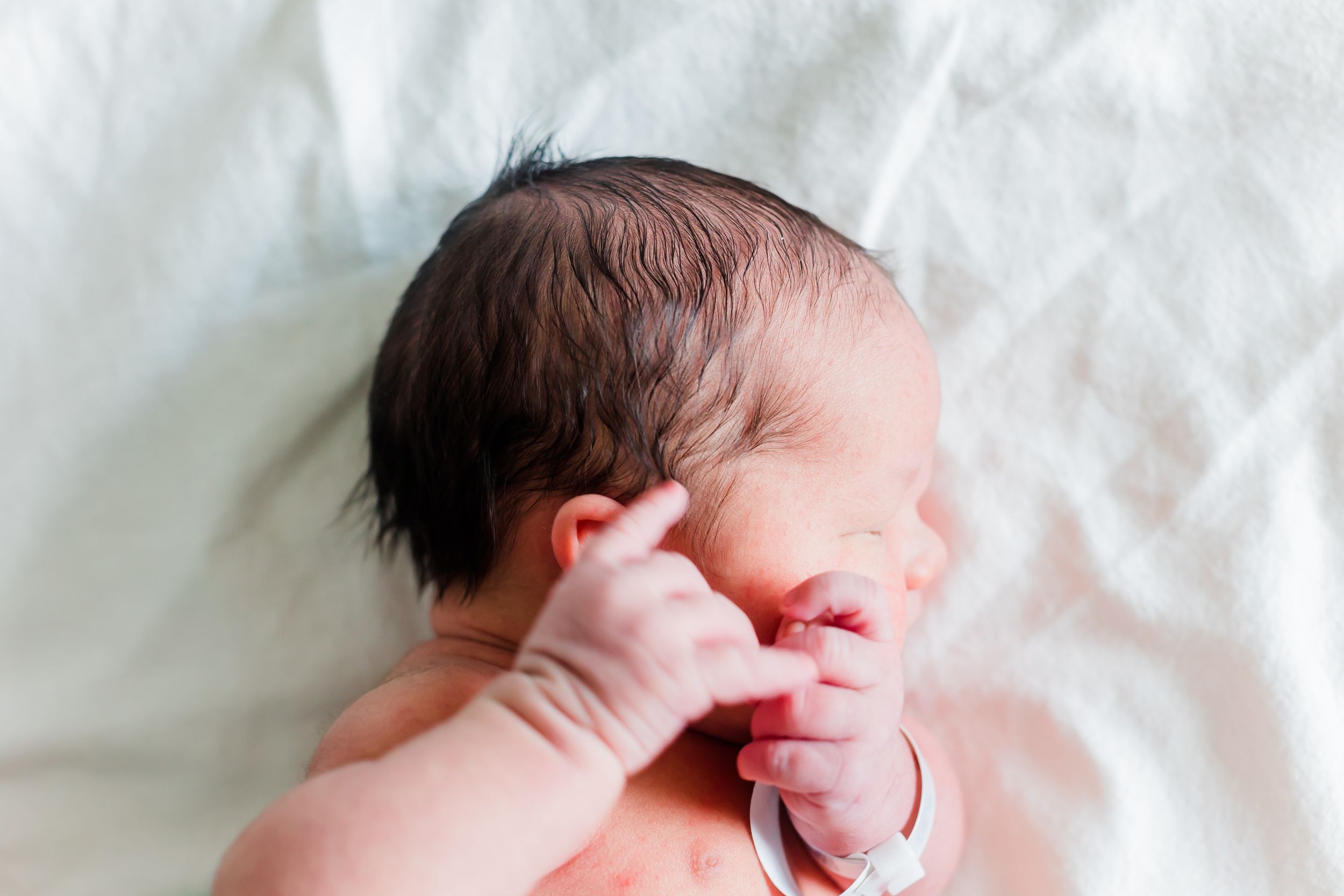 Sleeping newborn baby wrapped in soft white blanket.